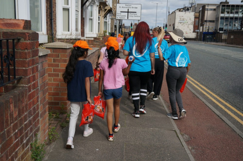 Group of volunteers and children walking down a road.